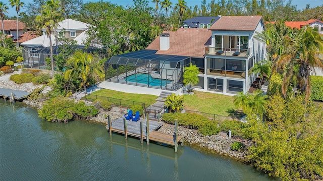 back of house featuring a balcony, a water view, a chimney, and a yard