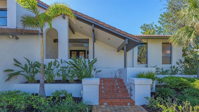 property entrance featuring a tiled roof and stucco siding