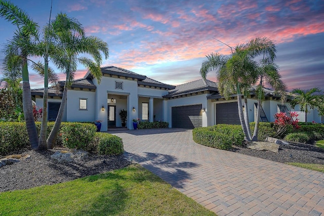 view of front facade featuring a garage, decorative driveway, and stucco siding