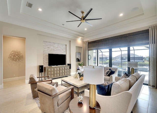 living room featuring visible vents, baseboards, a sunroom, ceiling fan, and a tray ceiling