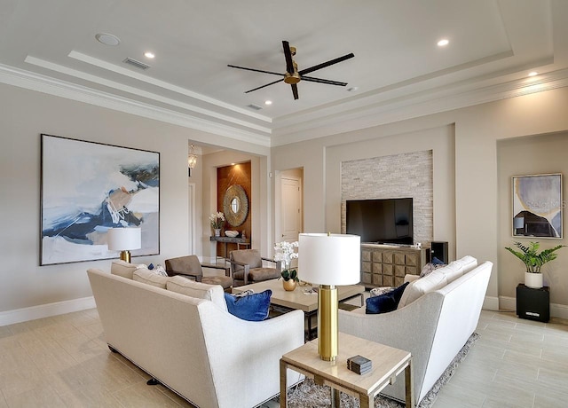 living room featuring ornamental molding, a tray ceiling, and baseboards