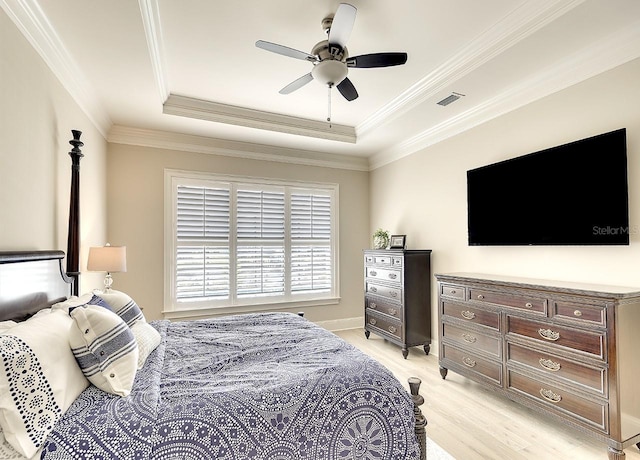 bedroom featuring visible vents, a raised ceiling, ceiling fan, crown molding, and light wood-type flooring