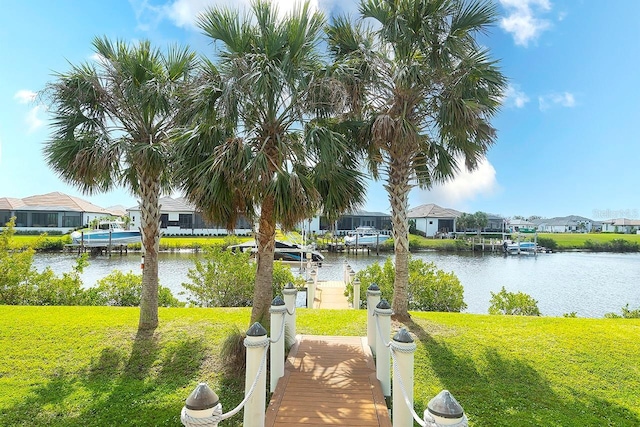 view of property's community with a yard, a boat dock, a water view, and a residential view