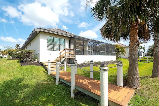 view of side of home with stairs, glass enclosure, a yard, and stucco siding