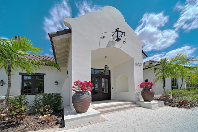 view of exterior entry featuring french doors and stucco siding