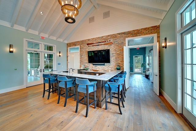 kitchen featuring light wood-style flooring, high vaulted ceiling, beam ceiling, and french doors