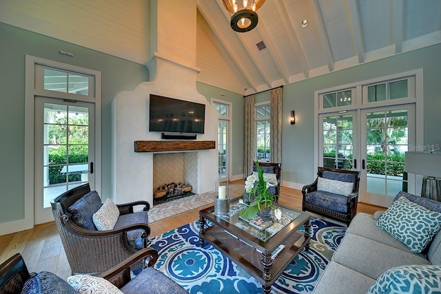 living room with a healthy amount of sunlight, a fireplace, high vaulted ceiling, and french doors