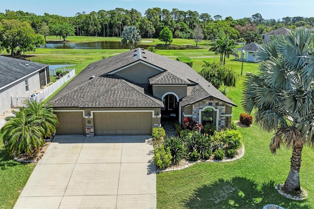 view of front of house featuring an attached garage, stone siding, concrete driveway, and a water view