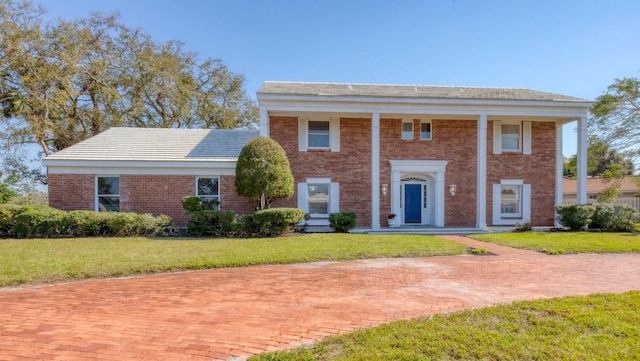 neoclassical home featuring a front yard and brick siding