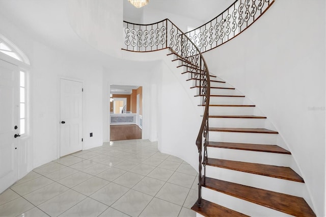 foyer entrance with a chandelier, tile patterned flooring, stairway, and a high ceiling