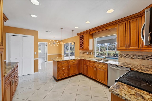 kitchen featuring a peninsula, dishwasher, brown cabinetry, and a sink