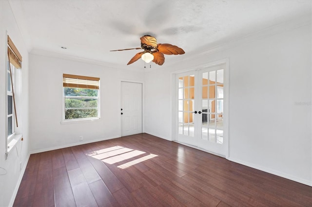 spare room with french doors, crown molding, dark wood-type flooring, a ceiling fan, and baseboards