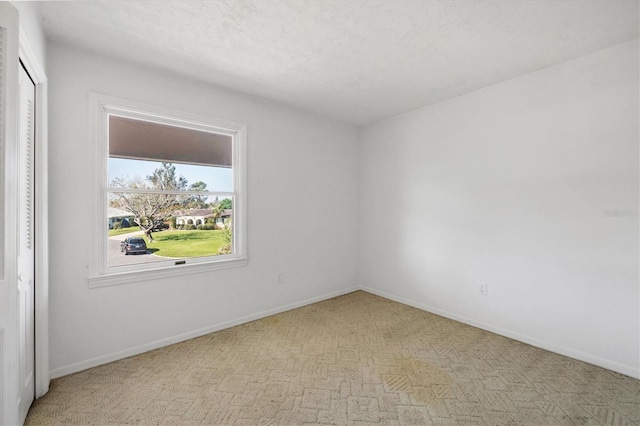 spare room featuring a textured ceiling and baseboards