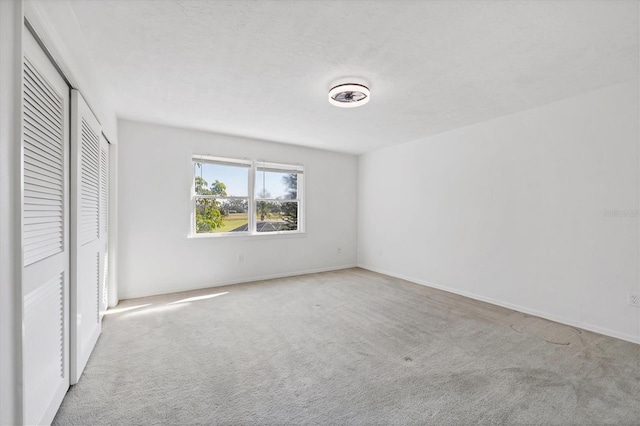 unfurnished bedroom with a textured ceiling, a closet, and carpet flooring