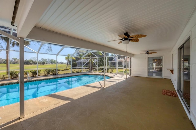 outdoor pool with glass enclosure, a patio area, and a ceiling fan