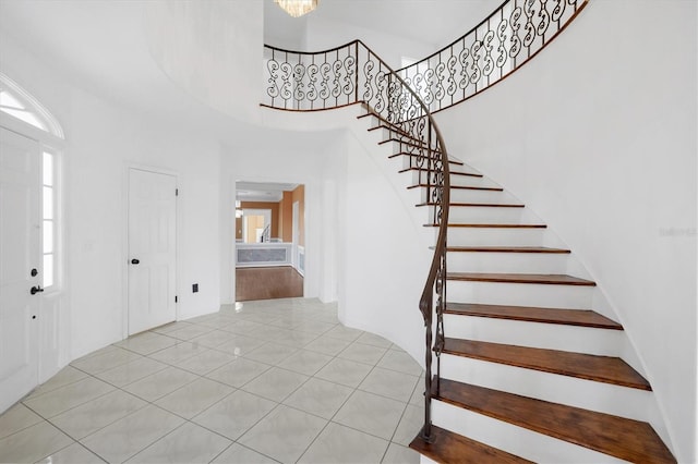 tiled foyer entrance featuring stairs and a towering ceiling