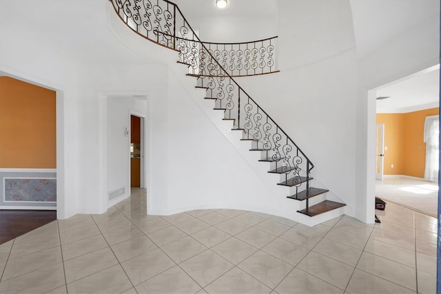 stairs featuring tile patterned flooring, baseboards, and a towering ceiling