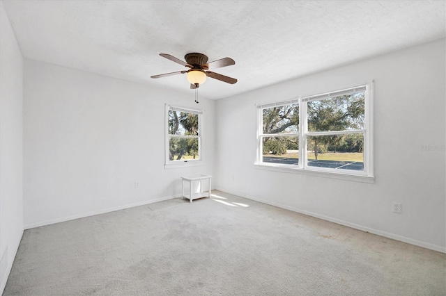 carpeted empty room with baseboards and a ceiling fan