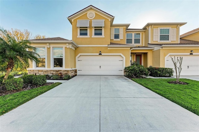 view of front facade featuring a garage, concrete driveway, a front yard, and stucco siding