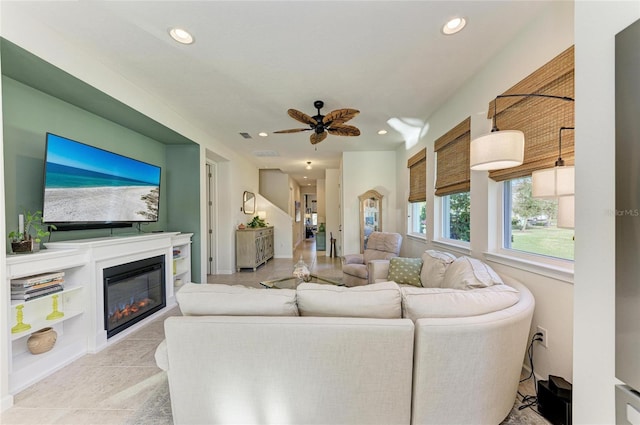 living area with recessed lighting, a ceiling fan, and a glass covered fireplace