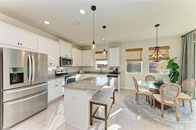 kitchen featuring white cabinets, stainless steel appliances, a sink, and a center island