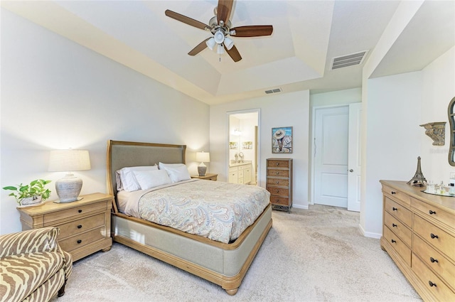 bedroom featuring a raised ceiling, visible vents, light carpet, and ensuite bath