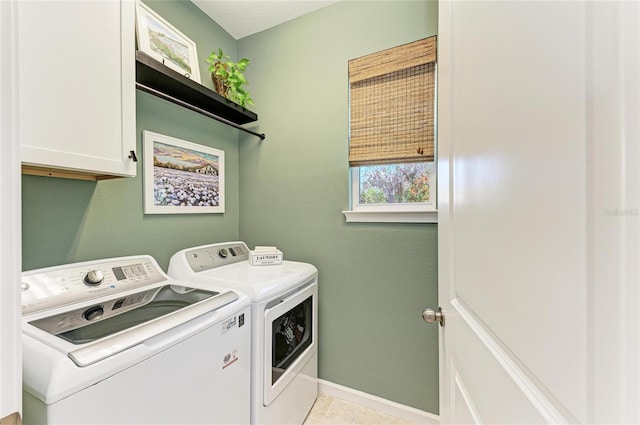 laundry area featuring light tile patterned floors, washing machine and dryer, cabinet space, and baseboards