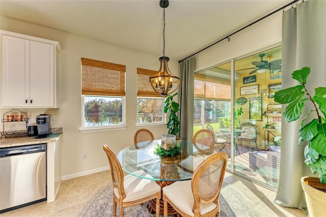 dining room with ceiling fan with notable chandelier, a wealth of natural light, and baseboards