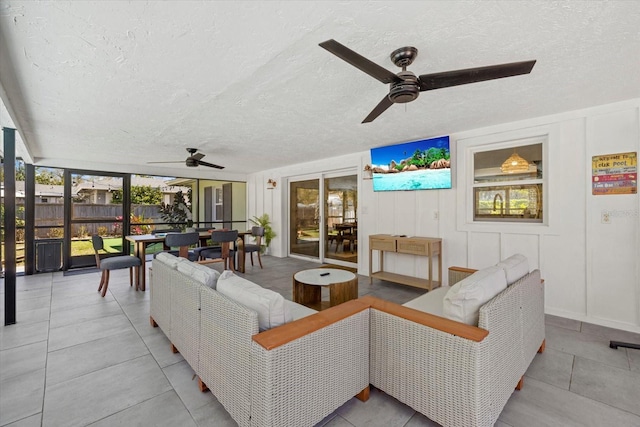 living room with ceiling fan, a textured ceiling, and a wealth of natural light