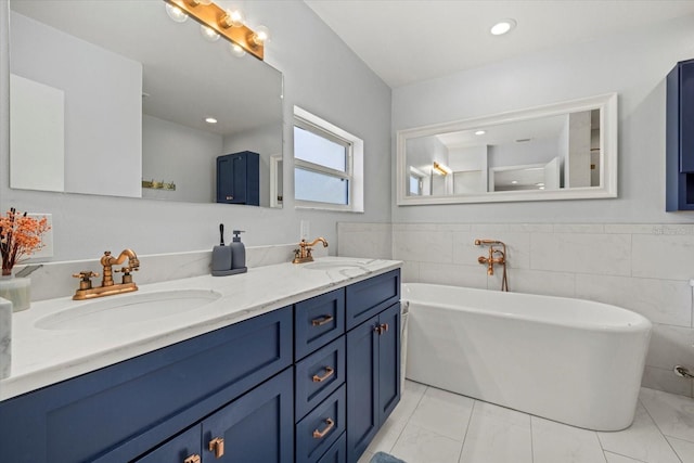 bathroom featuring double vanity, a freestanding tub, a sink, and tile walls