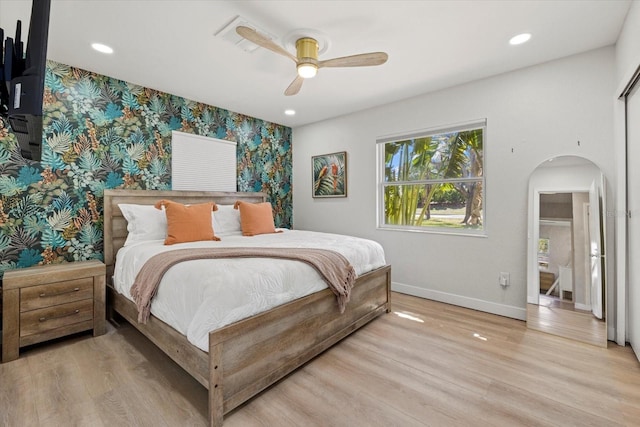 bedroom featuring wallpapered walls, baseboards, arched walkways, light wood-type flooring, and recessed lighting