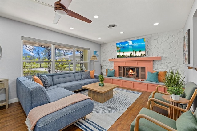 living room featuring recessed lighting, visible vents, wood finished floors, and a stone fireplace