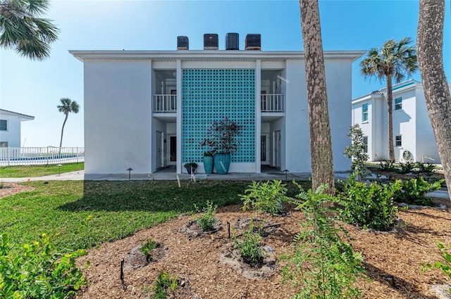 view of front of home with a patio, a balcony, fence, stucco siding, and a front yard