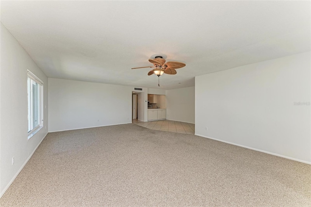 spare room with light carpet, ceiling fan, visible vents, and baseboards