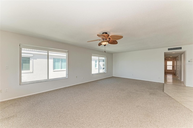 unfurnished room featuring light tile patterned floors, visible vents, light carpet, ceiling fan, and a textured ceiling