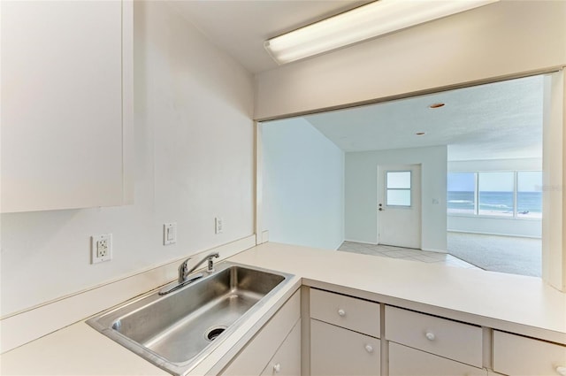 kitchen with white cabinets, light countertops, and a sink