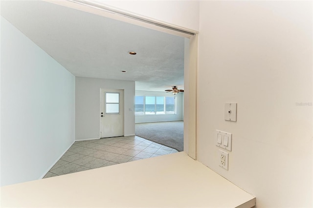 interior space with light carpet, light tile patterned flooring, and a ceiling fan