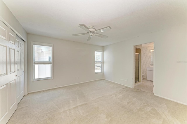 unfurnished bedroom featuring light carpet, ceiling fan, baseboards, and connected bathroom