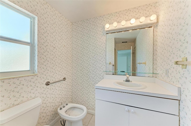 bathroom featuring wallpapered walls, toilet, tile patterned floors, vanity, and a bidet