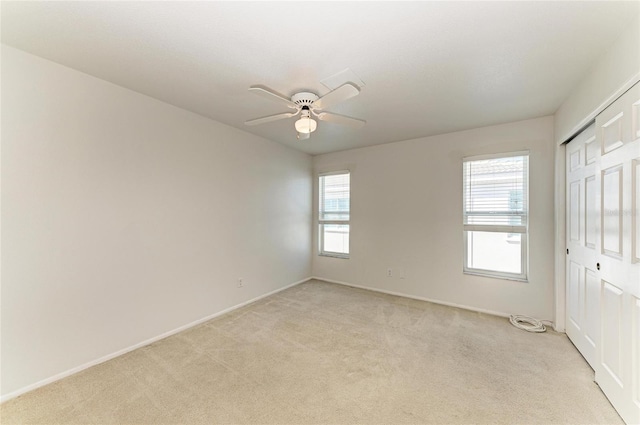 empty room with light carpet, a ceiling fan, and baseboards