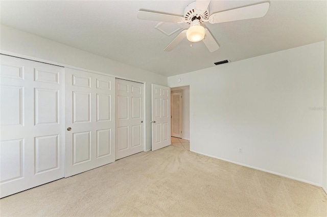 unfurnished bedroom featuring a ceiling fan, visible vents, a closet, and light colored carpet