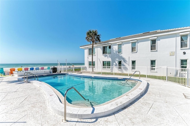 community pool with a water view, fence, and a patio