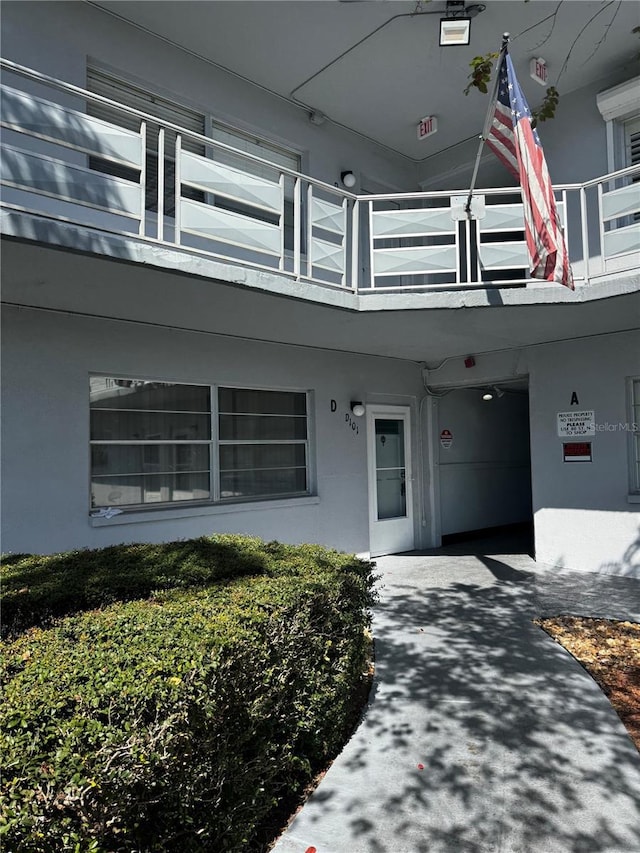 property entrance with a balcony and stucco siding