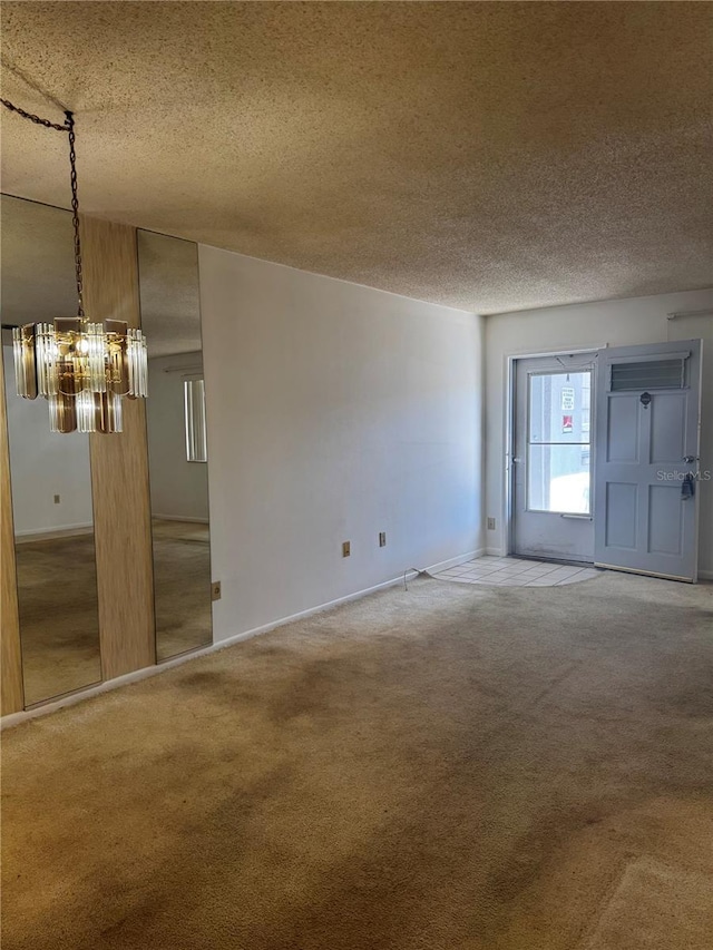 unfurnished room featuring baseboards, carpet, a chandelier, and a textured ceiling