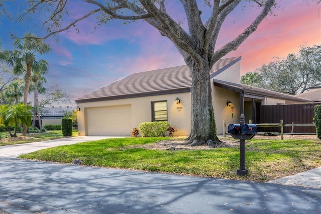 view of front of house featuring a garage, driveway, fence, and stucco siding