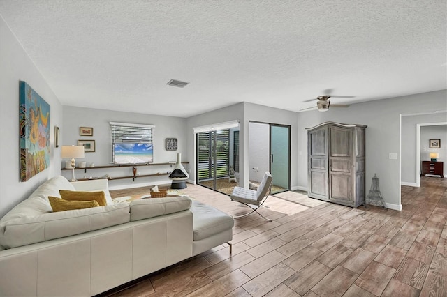 living area with visible vents, a textured ceiling, baseboards, and wood finished floors