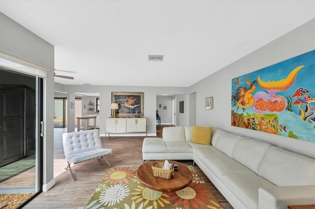 living area with wood finished floors, visible vents, and baseboards