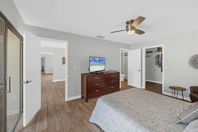 bedroom featuring baseboards, visible vents, a ceiling fan, wood finished floors, and a spacious closet