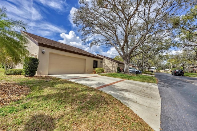 view of front of home featuring a garage, a front yard, driveway, and stucco siding