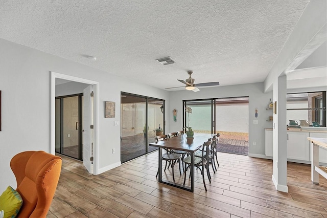 dining area with visible vents, wood tiled floor, ceiling fan, a textured ceiling, and baseboards